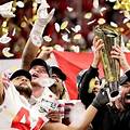 Players celebrating with the College Football Playoff championship trophy