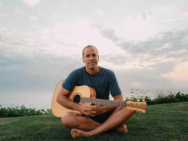 Johnson playing a sold-out show with ocean backdrop, embodying his signature coastal vibe.