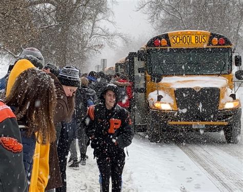 Students bundled up while waiting for a delayed school bus during winter weather conditions.