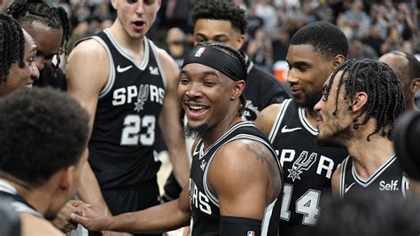 Spurs players watch intently as Wembanyama receives on-court treatment.